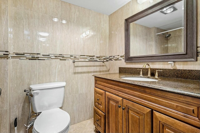 bathroom featuring tile patterned flooring, vanity, toilet, and tile walls