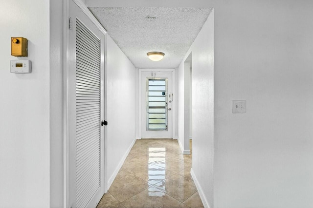 hallway with light tile patterned floors and a textured ceiling