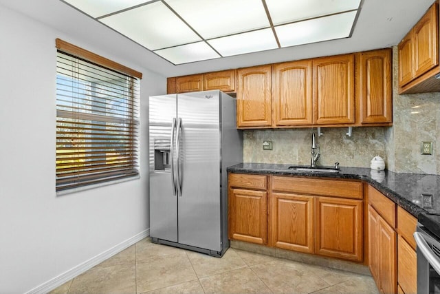 kitchen featuring dark stone counters, sink, light tile patterned floors, appliances with stainless steel finishes, and tasteful backsplash