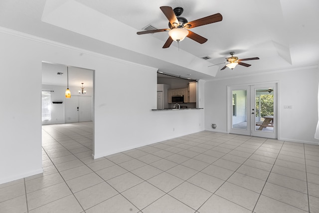 unfurnished living room featuring a tray ceiling, ceiling fan, crown molding, and light tile patterned flooring