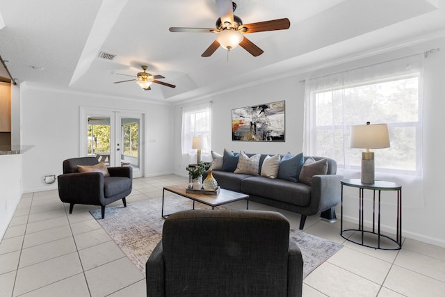 living room featuring french doors, a tray ceiling, crown molding, and light tile patterned flooring