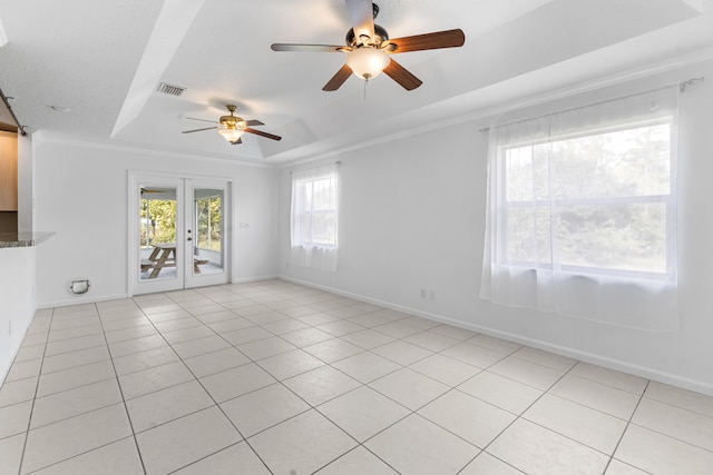 unfurnished room with light tile patterned floors, french doors, a tray ceiling, and plenty of natural light