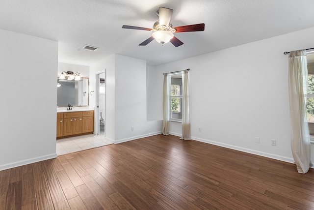 unfurnished bedroom featuring connected bathroom, ceiling fan, sink, a textured ceiling, and light wood-type flooring