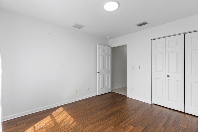 unfurnished bedroom with a closet and dark wood-type flooring