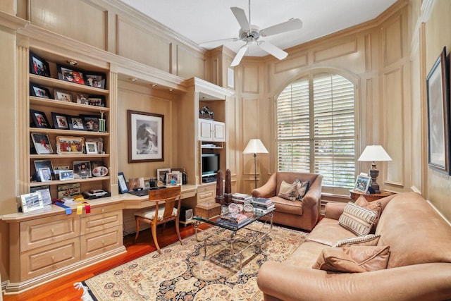 home office featuring built in shelves, ceiling fan, crown molding, light hardwood / wood-style floors, and built in desk