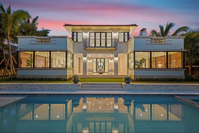 back house at dusk with a balcony