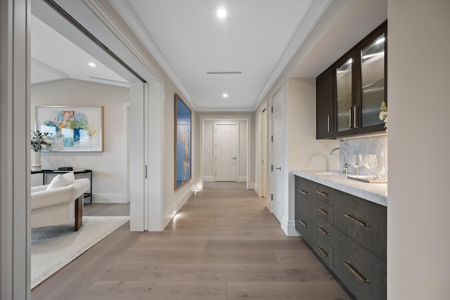 hall with ornamental molding, light hardwood / wood-style flooring, lofted ceiling, and sink