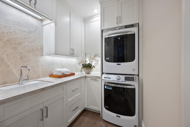 laundry room featuring cabinets, stacked washing maching and dryer, dark hardwood / wood-style floors, and sink