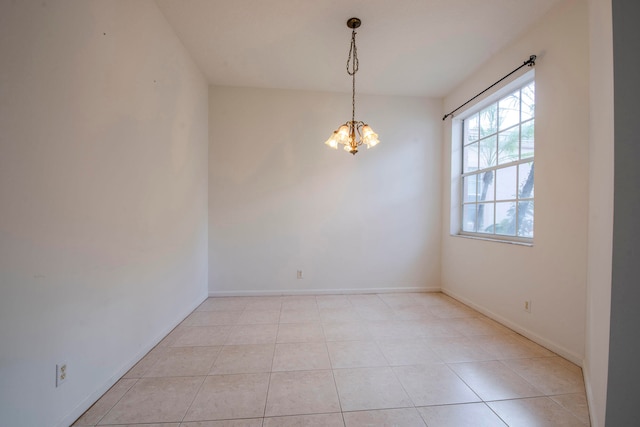 tiled spare room with a chandelier