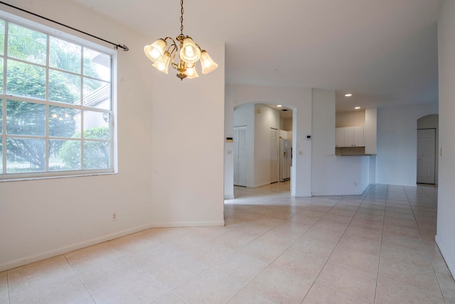 empty room featuring light tile patterned floors and a notable chandelier