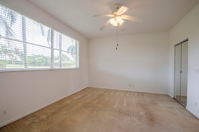 carpeted spare room featuring ceiling fan