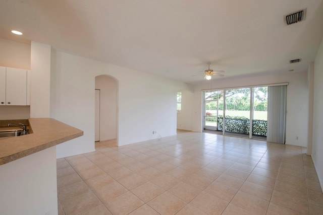 unfurnished living room featuring sink, light tile patterned floors, and ceiling fan