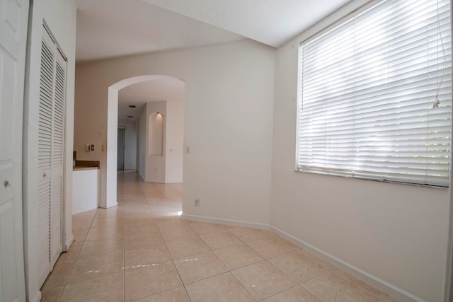 hall with a textured ceiling and light tile patterned floors