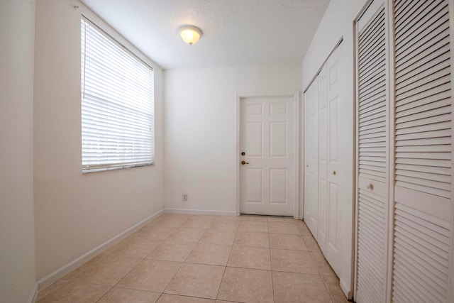 interior space with a textured ceiling and light tile patterned floors