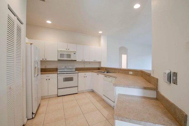 kitchen with white cabinetry, kitchen peninsula, light tile patterned floors, sink, and white appliances