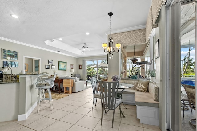 dining room with a tray ceiling, recessed lighting, light tile patterned flooring, and crown molding