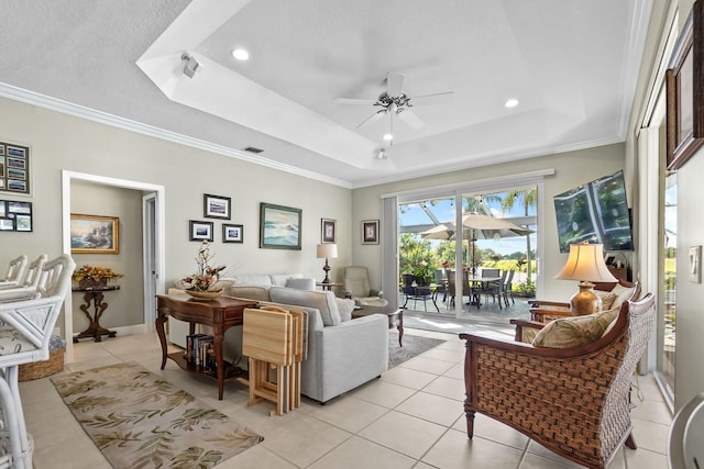 living room with ornamental molding, a raised ceiling, light tile patterned flooring, and ceiling fan