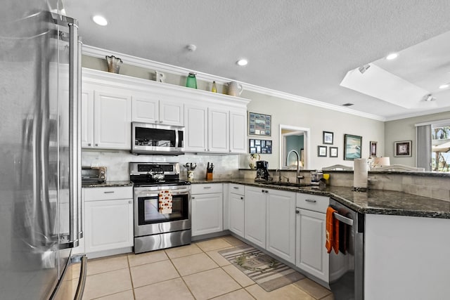 kitchen featuring stainless steel appliances, tasteful backsplash, ornamental molding, white cabinets, and a sink