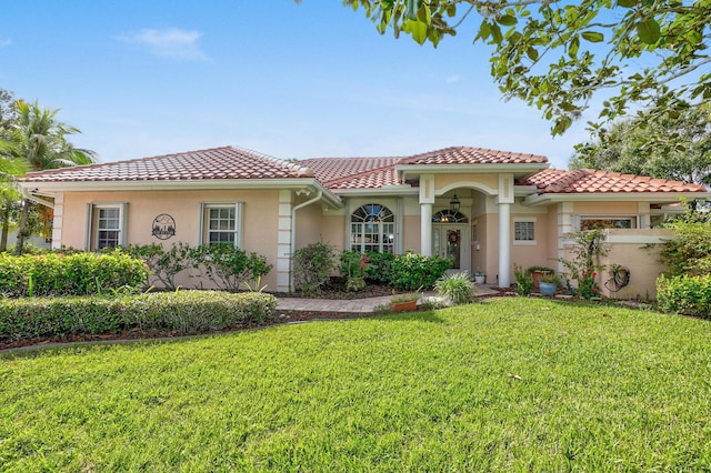 mediterranean / spanish-style house with a front yard, a tiled roof, and stucco siding