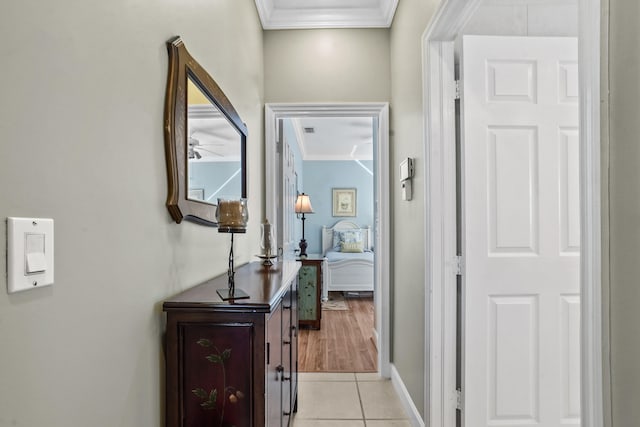 hall featuring light tile patterned floors and crown molding