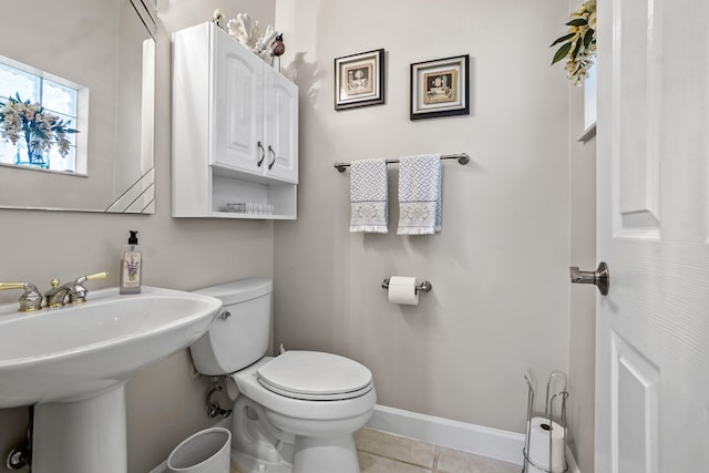 half bathroom featuring a sink, toilet, baseboards, and tile patterned floors