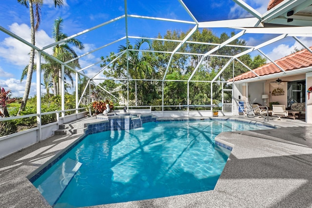 view of pool featuring glass enclosure, ceiling fan, a pool with connected hot tub, and a patio