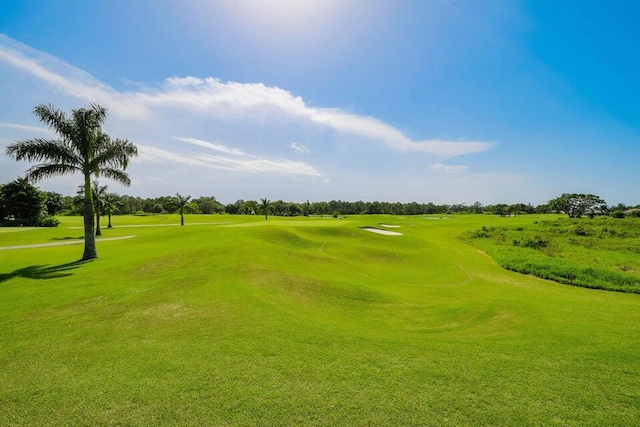 view of property's community featuring view of golf course and a lawn