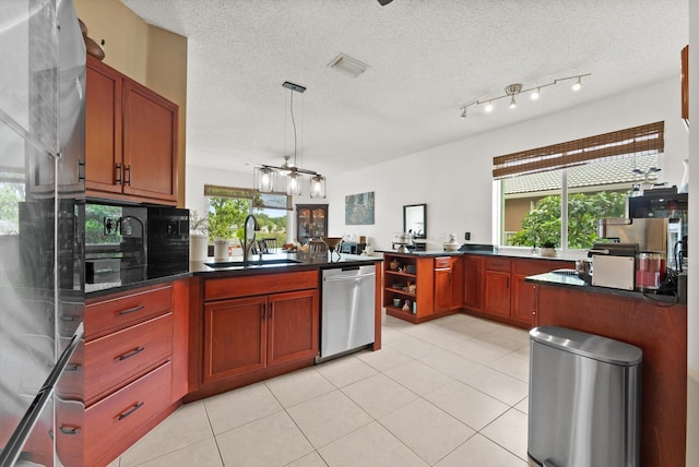 kitchen featuring a textured ceiling, sink, light tile patterned floors, and stainless steel appliances