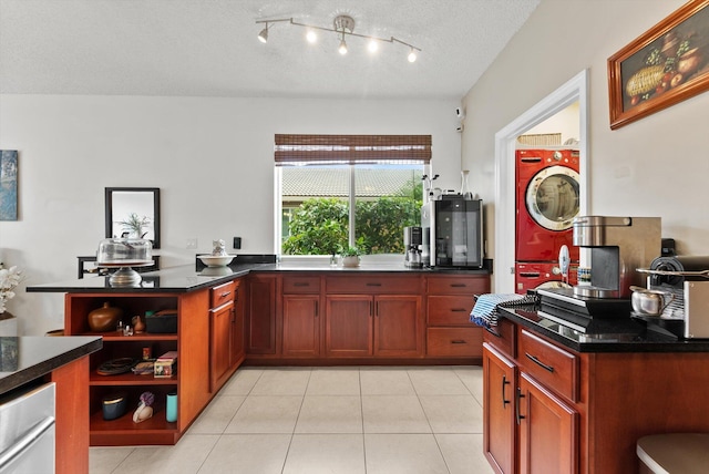 kitchen featuring stacked washer and dryer, light tile patterned floors, and a textured ceiling