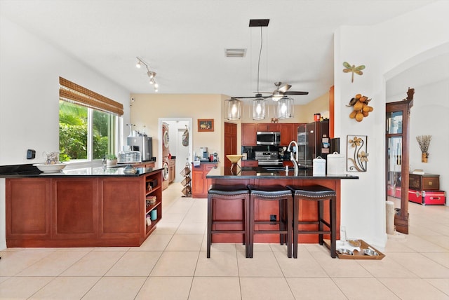 kitchen featuring hanging light fixtures, ceiling fan, light tile patterned floors, kitchen peninsula, and stainless steel appliances