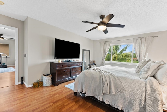 bedroom with a textured ceiling, light hardwood / wood-style flooring, and ceiling fan