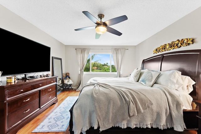 bedroom with a textured ceiling, light hardwood / wood-style flooring, and ceiling fan