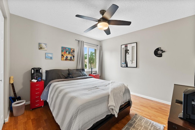 bedroom with ceiling fan, dark hardwood / wood-style flooring, and a textured ceiling