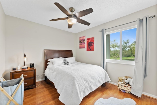 bedroom featuring ceiling fan, hardwood / wood-style floors, and a textured ceiling