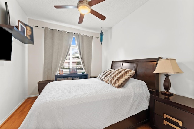 bedroom with a textured ceiling, light hardwood / wood-style flooring, and ceiling fan