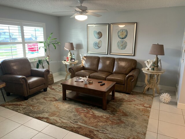 living room with ceiling fan, light tile patterned floors, and a textured ceiling