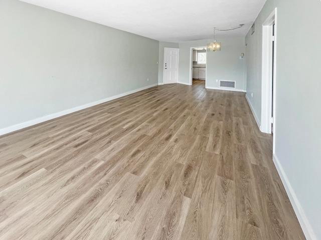 unfurnished living room featuring light wood-type flooring and a notable chandelier