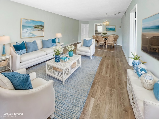 living room featuring a chandelier, light wood finished floors, and baseboards