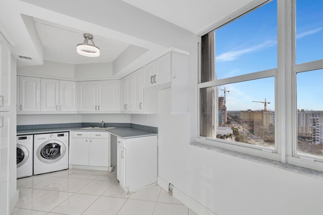 laundry area with cabinets, light tile patterned floors, sink, and washing machine and clothes dryer