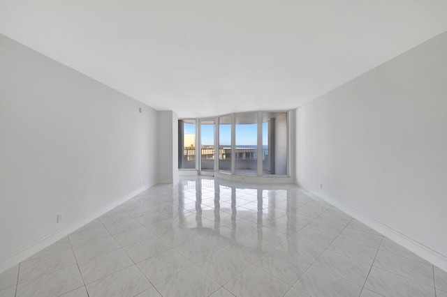 empty room featuring expansive windows and light tile patterned floors