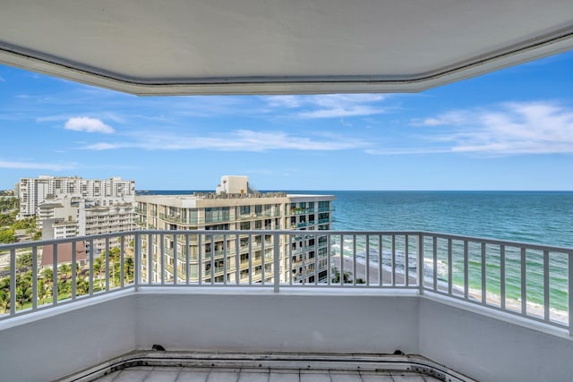 balcony with a water view and a view of the beach