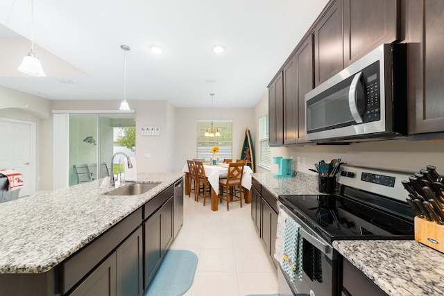 kitchen with sink, appliances with stainless steel finishes, hanging light fixtures, a chandelier, and a kitchen island with sink