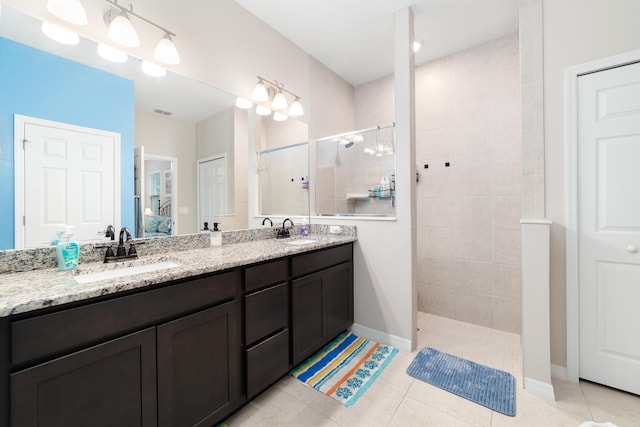 bathroom featuring a tile shower, vanity, and tile patterned floors