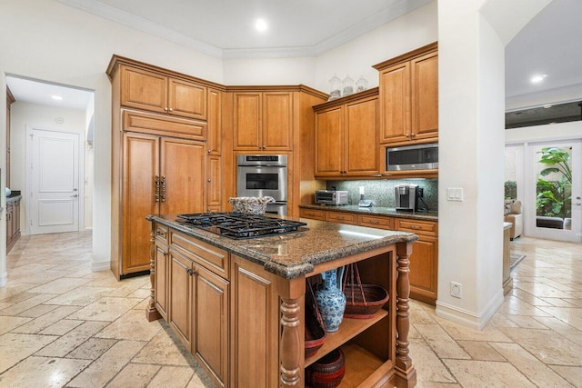 kitchen with crown molding, dark stone counters, a kitchen island, built in appliances, and decorative backsplash