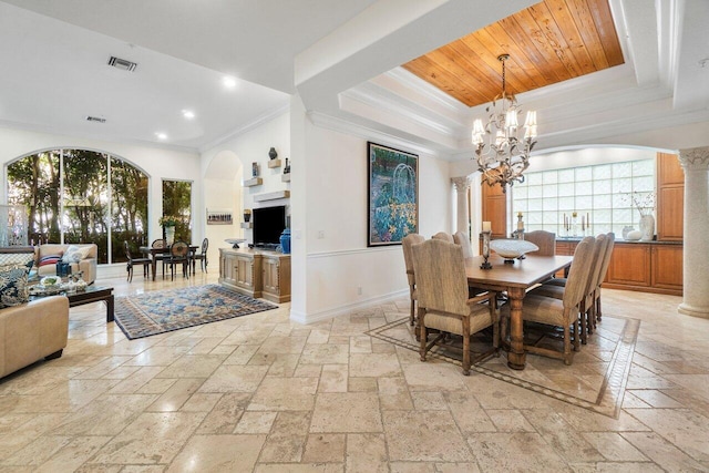 dining room with ornate columns, an inviting chandelier, crown molding, and a tray ceiling