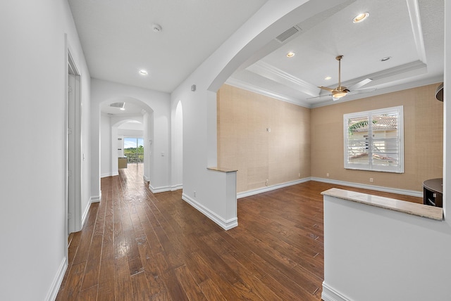 unfurnished living room featuring dark hardwood / wood-style floors, ceiling fan, a raised ceiling, and crown molding