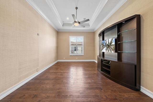 interior space with dark hardwood / wood-style flooring, a tray ceiling, ceiling fan, and ornamental molding