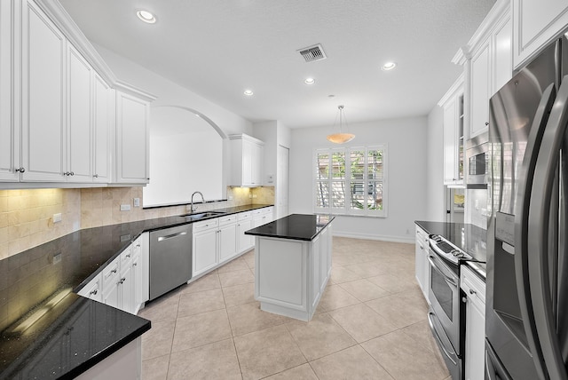 kitchen with a center island, sink, stainless steel appliances, pendant lighting, and white cabinets