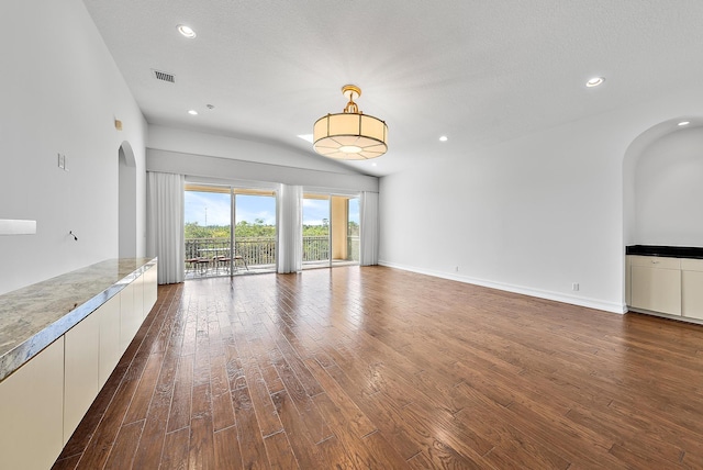 unfurnished living room featuring a textured ceiling and dark hardwood / wood-style floors