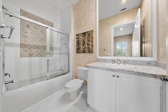 full bathroom with vanity, tile patterned floors, bath / shower combo with glass door, toilet, and tile walls